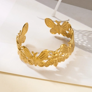 Detailed relief of butterflies and bees on a gold-plated stainless steel open cuff bracelet