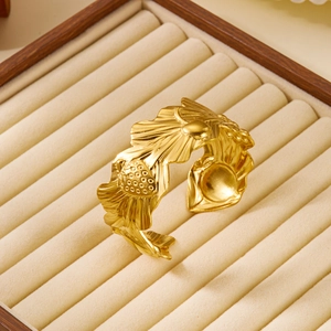 Detail of golden strawberry leaf open cuff bracelet on beige velvet jewelry box