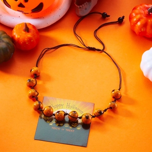 Close-up of Halloween necklace with orange spider web beads on festive card