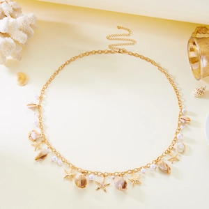 Detailed view of bohemian gold body chain with seashells, starfish and white pearls