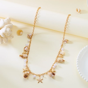 Close-up of golden beach body chain featuring sea shells, starfish charms and pearls