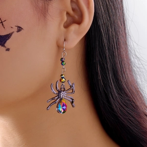 Détail macro de boucles d'oreilles araignée gothiques avec strass colorés sur un modèle