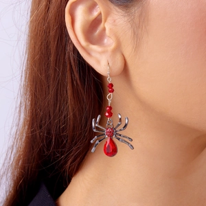 Détail de boucles d'oreilles araignée gothique avec cristaux rouges sur l'oreille