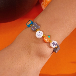 Detalle de una pulsera de Halloween hecha a mano con cuentas de calabaza y murciélago al pulso
