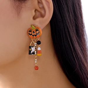 Detailed view of asymmetric Halloween earrings with pumpkin, ghost charm, and rhinestone tassel
