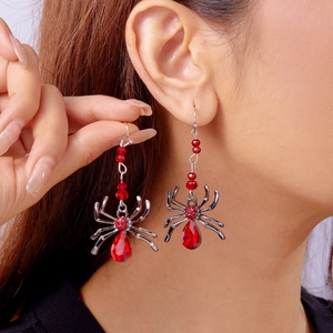 Détail macro de boucles d'oreilles araignée gothiques avec cristaux rouges sur modèle