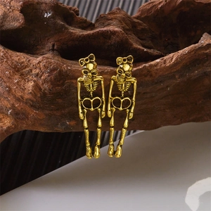 Detailopname van vintage gouden skelet oorbellen met strikjes op rustiek houten decor