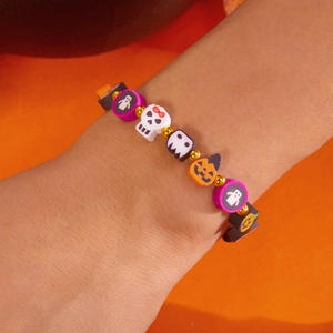 Pulsera de Halloween de cuentas de arcilla con dijes de calabaza, fantasma y calavera en la mano