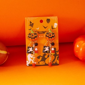Detail van Halloween pompoen oorbellen met parels en strass kwastjes op een oranje kaartje