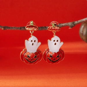 Detail of Halloween pumpkin earrings with ghosts hanging on a wooden branch