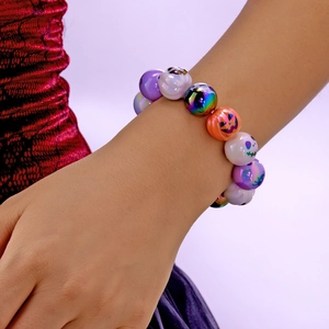 Detalle de pulsera de Halloween con cuentas moradas y naranjas y patrones de calabazas