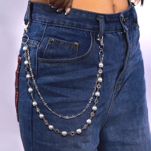 Détail de la chaîne de taille double couche en perles et strass sur un jean bleu