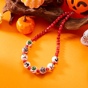 Detalle de collar de Halloween con cuentas pintadas de ojos y murciélagos en fondo naranja