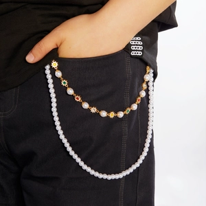 Détail d'une chaîne de pantalon double couche en perles avec gemmes sur jean noir