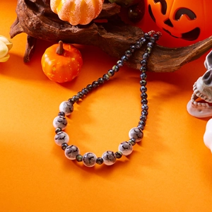 Detalle de collar de Halloween con silueta de murciélago sobre fondo temático naranja
