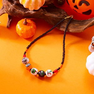 Collar de cuentas de Halloween con murciélagos, ojos y gatos sobre madera oscura