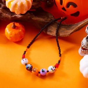 Detalle de collar de Halloween con motivos de fantasmas y calabazas en fondo naranja