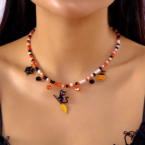 Halloween beaded necklace with pumpkin, black cat, and spider web charms worn by model