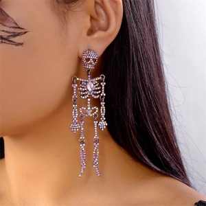 Dettaglio di orecchini a scheletro gotico con strass colorati indossati da una modella