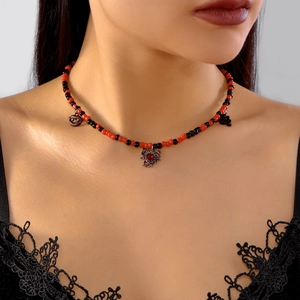 Detail of Halloween beaded necklace with spider web, bat and red lip charms on model