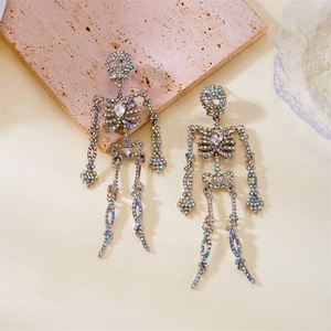Dettaglio degli orecchini a teschio argento con strass colorati su uno sfondo con texture