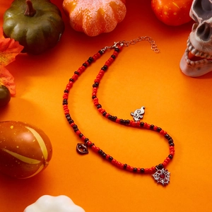 Close-up of Halloween beaded necklace with ghost, lips and spider web metal charms