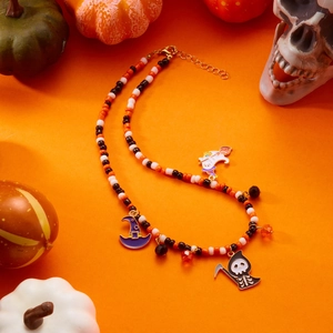 Detailed shot of Halloween beaded necklace with ghost and pumpkin charms on orange surface