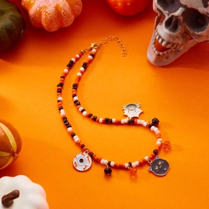 Detail of Halloween beaded necklace with spider, eyeball and black cat charms in orange