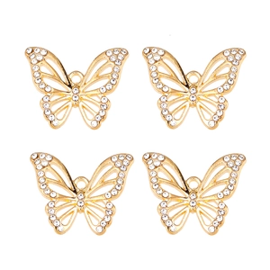 Détail de quatre pendentifs papillons dorés avec cristaux blancs pour création de bijoux DIY