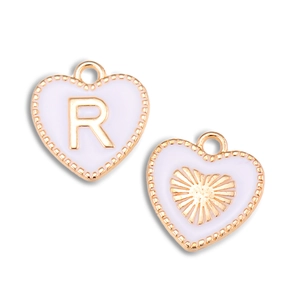 Detail van hartvormige paarse emaille hangers met gouden letter R en zonnestraalmotief