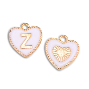 Detail van hartvormige witte emaille hanger met gouden letter Z en zonnestraal patroon