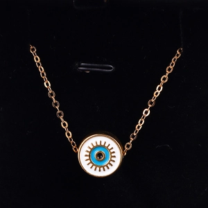 Macro detail of golden Evil Eye pendant with blue enamel inlay on a black display