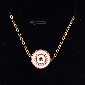 Macro shot of gold-plated evil eye necklace with pink enamel and radial eyelashes detail