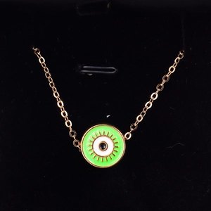 Detailed close-up of a gold Evil Eye pendant with vibrant neon green enamel on black velvet
