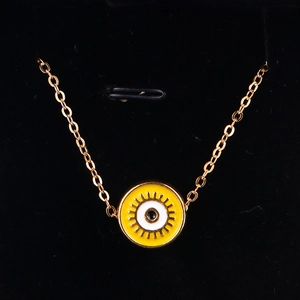 Detail of gold evil eye pendant with yellow enamel finish on black velvet background