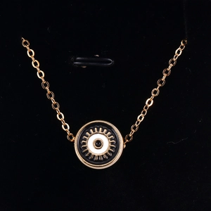 Macro shot of gold evil eye pendant with black and white enamel detail on velvet