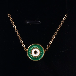 Macro detail of gold evil eye pendant necklace with green enamel on black velvet