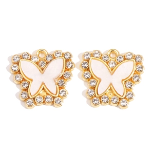 Macro detail of butterfly pendants with gold alloy, white enamel and sparkling rhinestones