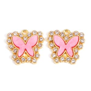 Macro view of butterfly pendant charms with pink enamel and clear crystal borders