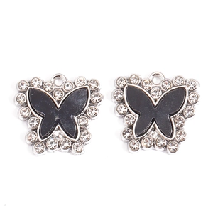 Detailed macro view of two butterfly charms with silver base and black enamel with rhinestones
