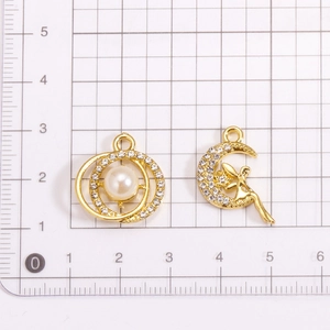 Golden moon and fairy alloy pendants with pearls and rhinestones on a grid background