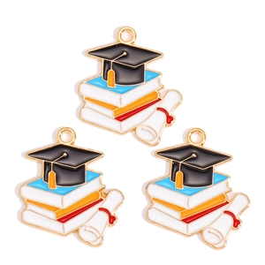 Detail view of enamel graduation cap and books pendants for DIY jewelry crafting