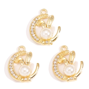 Close-up of alloy moon and rabbit pendants with pearls and rhinestones for DIY jewelry