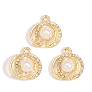 Detailed view of three gold alloy pendants with white pearls and micro-zirconia insets