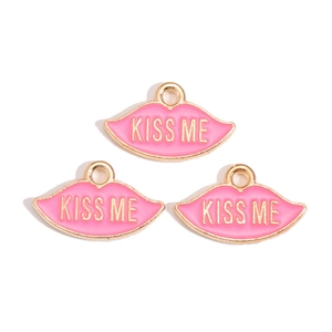 Dettaglio di tre ciondoli labbra in smalto rosa con scritta Kiss Me dorata per gioielli