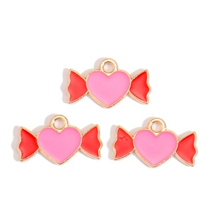 Close-up of heart-shaped candy charms with pink enamel and red wings for DIY jewelry