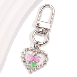 Détail d'un porte-clés en forme de cœur avec cristaux et fleurs de tulipes en résine rose