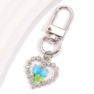 Détail du porte-clés cœur argenté avec tulipes bleues et strass sur fond blanc