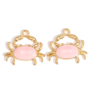 Gros plan de pendentifs crabe en émail rose dorés pour la création de bijoux