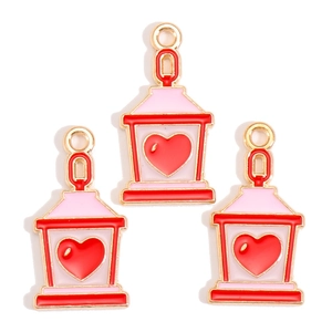 Detailed macro view of three gold-plated cartoon house charms with red and pink enamel hearts